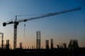 Industrial construction cranes and building silhouettes over sun at sunrise Royalty Free Stock Photo