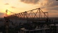 Industrial construction cranes and building silhouettes over sunset background and sunrise