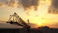 Industrial construction cranes and building silhouettes over sunset background and sunrise