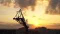 Industrial construction cranes and building silhouettes over sunset background and sunrise