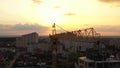 Industrial construction cranes and building silhouettes over sunset background and sunrise