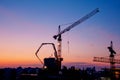 Industrial construction cranes and building silhouettes at sunrise or sunset Royalty Free Stock Photo