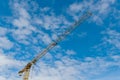 Industrial construction yellow tower crane with long boom with stiffeners, concrete counterweight blocks and hanging hooks. Royalty Free Stock Photo