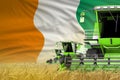 3 green modern combine harvesters with Cote d Ivoire flag on grain field - close view, farming concept - industrial 3D