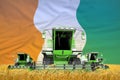 Four light green combine harvesters on rural field with flag background, Cote d Ivoire agriculture concept - industrial 3D