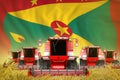 Industrial 3D illustration of some red farming combine harvesters on rye field with Grenada flag background - front view, stop