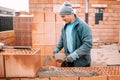 Construction bricklayer worker building house walls with bricks, mortar and rubber hammer Royalty Free Stock Photo