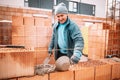 Construction bricklayer worker smiling and building walls with bricks, mortar and rubber hammer Royalty Free Stock Photo