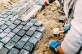 Industrial construction site - worker laying granite stones as walking path