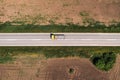 Industrial dump truck with empty trailer on highway through countryside landscape, drone pov aerial shot directly above. Industry