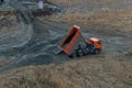 Industrial dumper truck working on highway construction site, loading and unloading gravel and earth