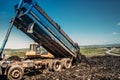 Industrial dumper trucks unloading garbage into trash hill