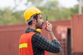 Industrial engineer in hard hat containers box background, Dock worker man talks on two-way radio at containers cargo, Logistic