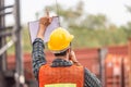 Industrial engineer in hard hat containers box background, Dock worker man talks on two-way radio with holding clipboard checklist