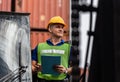 Industrial engineer in hard hat control loading containers box on stacker lifting cargo container, Dock worker man with clipboard