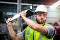 Industrial engineer worker wearing helmet and safe glasses, getting mad, hot temper, want destroy laptop computer at manufacturing