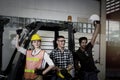 Industrial engineer worker woman and men wearing helmet, reaching arms up, standing next to factory forklift car, working together