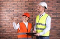 Industrial engineers in uniforms with clipboard on brick wall background