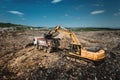 Industrial excavator loading dumper trucks with garbage Royalty Free Stock Photo