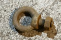 An industrial eyebolt lies on a concrete surface.