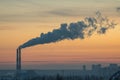 Industrial facility at dusk, two chimneys emitting smoke, utilitarian structures, cityscape in background, soft diffused light Royalty Free Stock Photo