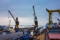 Industrial floating dock in a shipyard, cranes towering above. Vessel under repair, maritime equipment visible. Overcast Royalty Free Stock Photo