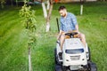 Industrial gardener driving a riding lawn mower in a garden Royalty Free Stock Photo