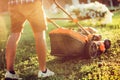 Industrial gardening and landscaping. Caucasian Gardener working with lawnmower and cutting grass during summer