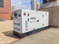 An industrial generator, predominantly white with KOHLE label and operational status indicators, is shown in an urban Royalty Free Stock Photo