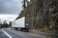 Industrial grade big rig yellow semi truck with dry van semi trailer running on the wet winding mountain road in rain weather Royalty Free Stock Photo