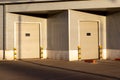 Industrial gray unit facade of storehouse with closed white metal gates doors at sunset Royalty Free Stock Photo