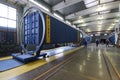 Cargo containers set in a frames of rotating machines for repairing, workers standing in the middle of the maintenance