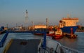 Industrial harbor with moored large ships with masts, barges with cargo, boats in red light of sunset. General view from ferry Royalty Free Stock Photo