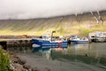 The industrial harbour of the Isafjordur in Iceland with a yachts, blue boat IS141 and mountain covered in misty clouds