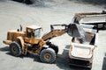 Industrial heavy duty large wheel loader moving gravel and loading dumper trucks at work site Royalty Free Stock Photo