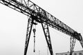 Industrial iron large metal gantry crane with a hook mounted on the supports for lifting and carrying heavy cargo Royalty Free Stock Photo