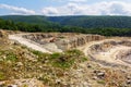 Industrial landscape with an excavator in quarry for the extraction of limestone, gypsum and marble on a summer