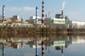 Industrial landscape. A large factory with pipes is reflected in the clear river water against the blue sky. Toxic smoke is coming Royalty Free Stock Photo