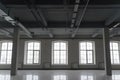 Empty open space in old factory building with columns, large windows and pipes under the beton ceiling Royalty Free Stock Photo