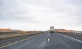 Big rig semi truck transporting loaded semi trailer driving on the straight highway road between winter fields with snow Royalty Free Stock Photo