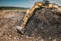 Industrial machinery excavating garbage. Close up of heavy duty excavator using scoop and working