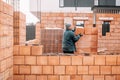 Industrial male bricklayer installing bricks on construction site. Royalty Free Stock Photo