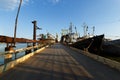 Pontoon bridge leads to shipyard, vessels undergo repairs under clear sky. Industrial maritime infrastructure supports