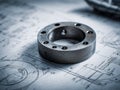 Industrial metal ring component resting on detailed engineering blueprints featuring technical drawings and precise mechanical Royalty Free Stock Photo