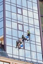 Industrial mountaineering worker cleaning window outside building. Royalty Free Stock Photo