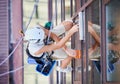 Industrial mountaineering worker cleaning window outside building. Royalty Free Stock Photo