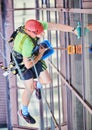 Industrial mountaineering worker cleaning window outside building. Royalty Free Stock Photo