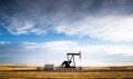 industrial oil pump jack working on farm land Royalty Free Stock Photo