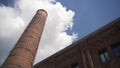 Industrial old red brick chimney on blue cloudy sky background. Action. Bottom view of an old abandoned factory building Royalty Free Stock Photo