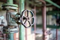 Industrial pipeline flanges hand wheel and valve close up, blur industrial pipelines background. Old rusty control